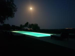 a swimming pool lit up at night with a moon at Terre Di Vendicari in Noto