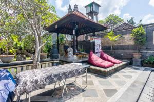 a patio with a bench with red pillows on it at Sagitarius Inn in Ubud