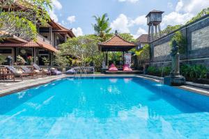een zwembad in een resort met stoelen en een gebouw bij Sagitarius Inn in Ubud