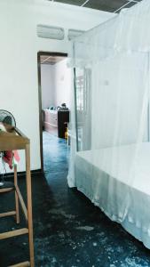 a bedroom with a bed with white curtains and a mirror at New Sam Tourist Inn in Weligama