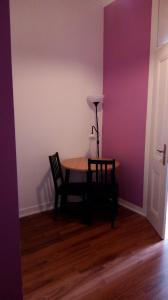uma mesa e cadeiras num quarto com uma parede roxa em Cenário Catita Hostel em Lisboa