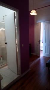 里斯本的住宿－塞納里奧卡迪塔旅舍，通向带紫色墙壁的房间的开放式门