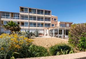 un edificio de apartamentos con jardín frente a él en Hotel Les Dunes en Marseillan