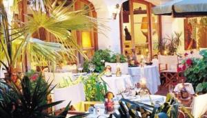 a restaurant with white tables and potted plants at Mangio Fango Hotel et Spa in Saintes-Maries-de-la-Mer