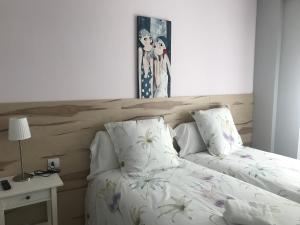 a bed with two pillows and a picture on the wall at Alojamientos Olga in Pamplona
