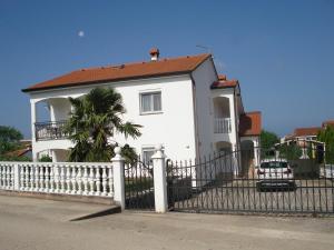 een wit huis met een wit hek en een palmboom bij Apartmani i soba Mia Poreč in Poreč