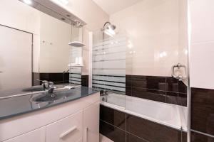La salle de bains est pourvue d'un lavabo, d'un miroir et d'une baignoire. dans l'établissement Hotel Les Dunes, à Marseillan