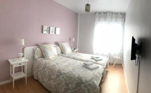 a white bedroom with a bed and a window at Alojamientos Iruña in Pamplona