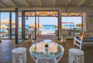 una habitación con una mesa de cristal y sillas y la playa en Kokkari Beach Hotel, en Kokkari