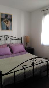 una camera da letto con un letto con cuscini viola e una finestra di Le Villette di Consuelo a Pizzolungo