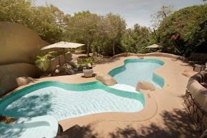 a swimming pool with chairs and an umbrella at Olarro Lodge in Maji Moto