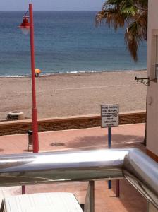 a view of a beach with a sign on a fence at Apartamentos Delamar in Carboneras
