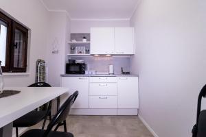 a kitchen with white cabinets and a table and chairs at Apartments Bella Tara in Piran