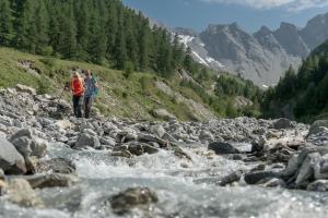 two people standing on a river with rocks at Chalet Silvretta Hotel & Spa in Samnaun