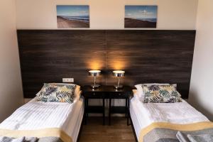 een kamer met 2 bedden en een bureau met 2 lampen bij Black Beach Guesthouse in Þorlákshöfn