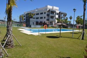 una piscina en un parque junto a un edificio en Residencial Costa Doñana (Sanlucar de Barrameda), en Sanlúcar de Barrameda