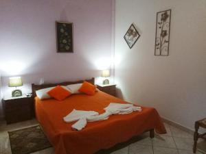 a bedroom with a bed with orange sheets and towels on it at Gramvousa's Filoxenia Apartment in Kissamos