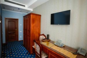 a hotel room with a desk and a television on the wall at Salut Hotel Almaty in Almaty