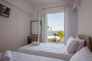 two beds in a room with a view of the ocean at Studios Angeliki in Lassi