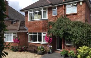 a red brick house with white windows and flowers at Honey Lodge in Broadstone