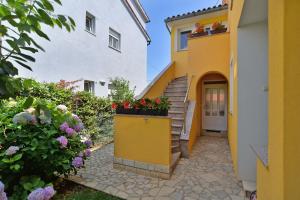 a house with a yellow door and flowers at Apartments Milena 436 in Fažana