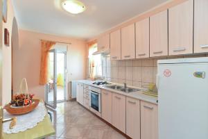 a kitchen with white cabinets and a refrigerator at Apartments Milena 436 in Fažana