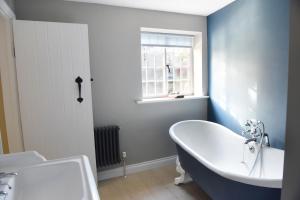 a bathroom with a tub and a sink and a window at The Three Horseshoes in Warham