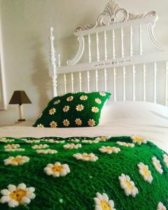 ネーラスにあるOutrora a Casa da Malvinaの花の上に緑の毛布が敷かれたベッド