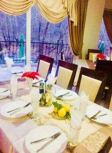uma mesa com pratos e utensílios brancos e uma janela em Villa Bella Boutique Hotel em Kavadarci