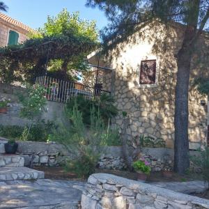 a stone house with a tree and a stone wall at Apartments Elena & Damir in Vis