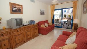 een woonkamer met een tv en 2 rode stoelen bij Mykonos Playa 18 in Manilva