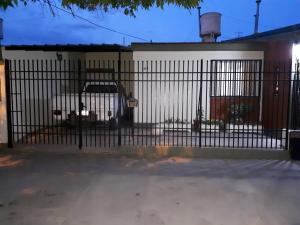 una cerca con un coche estacionado frente a un edificio en Casa Temporaria en San Rafael