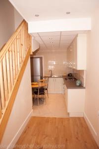 uma cozinha com armários brancos, uma mesa e uma escada em Home from Home em Ilford