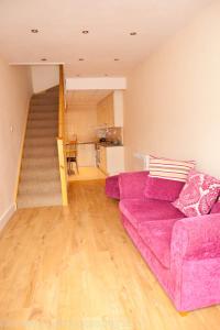 a living room with a purple couch and a staircase at Home from Home in Ilford