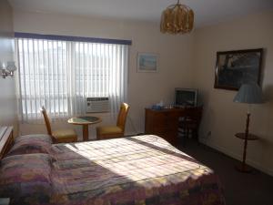 Schlafzimmer mit einem Bett, einem Tisch und einem Schreibtisch in der Unterkunft Hotel Harbour Grace in Harbour Grace