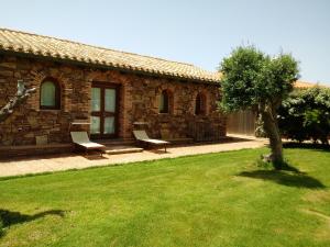 a stone house with two chairs and a tree at Hotel Corsaro Nero in Portu Maga