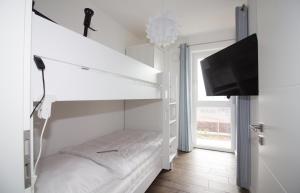 a white room with a bunk bed and a flat screen tv at Wohnen am Yachthafen W46 in Cuxhaven