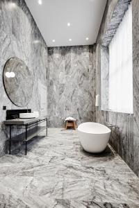 コペンハーゲンにあるNobis Hotel Copenhagen, a Member of Design Hotels™の大理石の壁のバスルーム(バスタブ付)