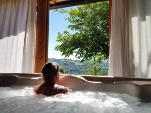 Ein Kind befindet sich in einer Badewanne mit Fenster. in der Unterkunft Les Hôtes du Lac, Chambres et tables d'hôtes in Mandailles