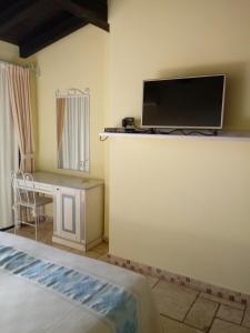 a bedroom with a bed and a desk and a tv at Hotel Corsaro Nero in Portu Maga
