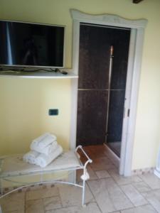 a room with a tv and a chair with towels at Hotel Corsaro Nero in Portu Maga