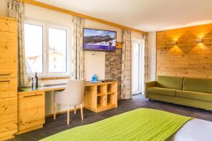 a bedroom with a couch and a desk and a tv at Hotel Hubertus in Sankt Johann im Pongau