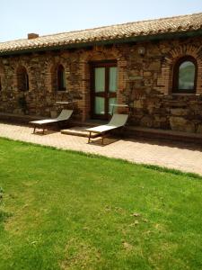 two benches sitting in front of a stone building at Hotel Corsaro Nero in Portu Maga