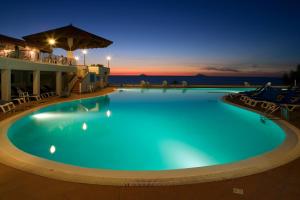 焦约萨马雷阿TH Gioiosa Mare - Capo Calavà Village的夜间带椅子的大型游泳池