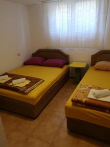two beds sitting in a room with a window at Ori in Podgorica