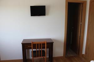 a table with a chair and a television on a wall at Hostal Mirobriga in Ciudad-Rodrigo