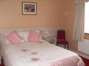 a bedroom with a white bed with pink pillows at The Purple Heather B&B in Beaufort