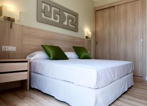 a bedroom with a large white bed with green pillows at Camping Villasol in Benidorm