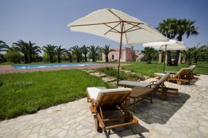 einen Tisch und Stühle mit einem Sonnenschirm und einem Pool in der Unterkunft Villa I Giardini di Marzo in Guagnano