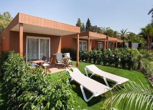 a house with a lawn and two lounge chairs at Camping Villasol in Benidorm